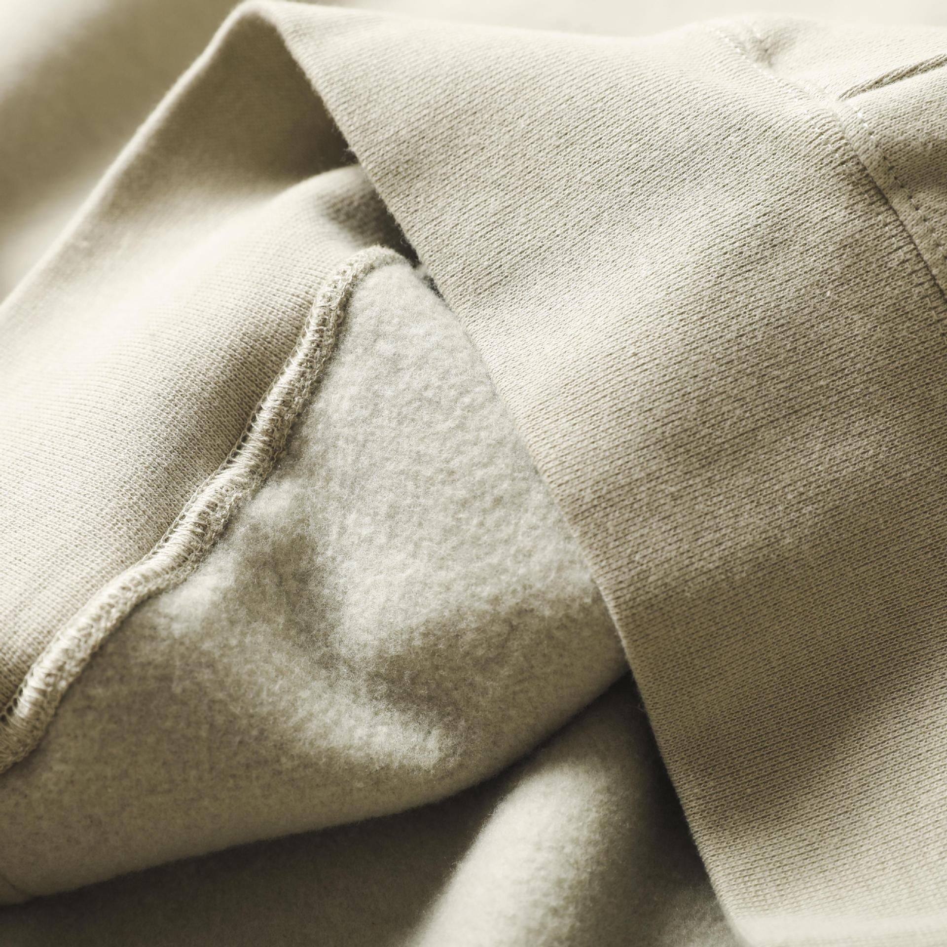 Soft, cozy beige hoodie with drawstring and fabric folds in the image.