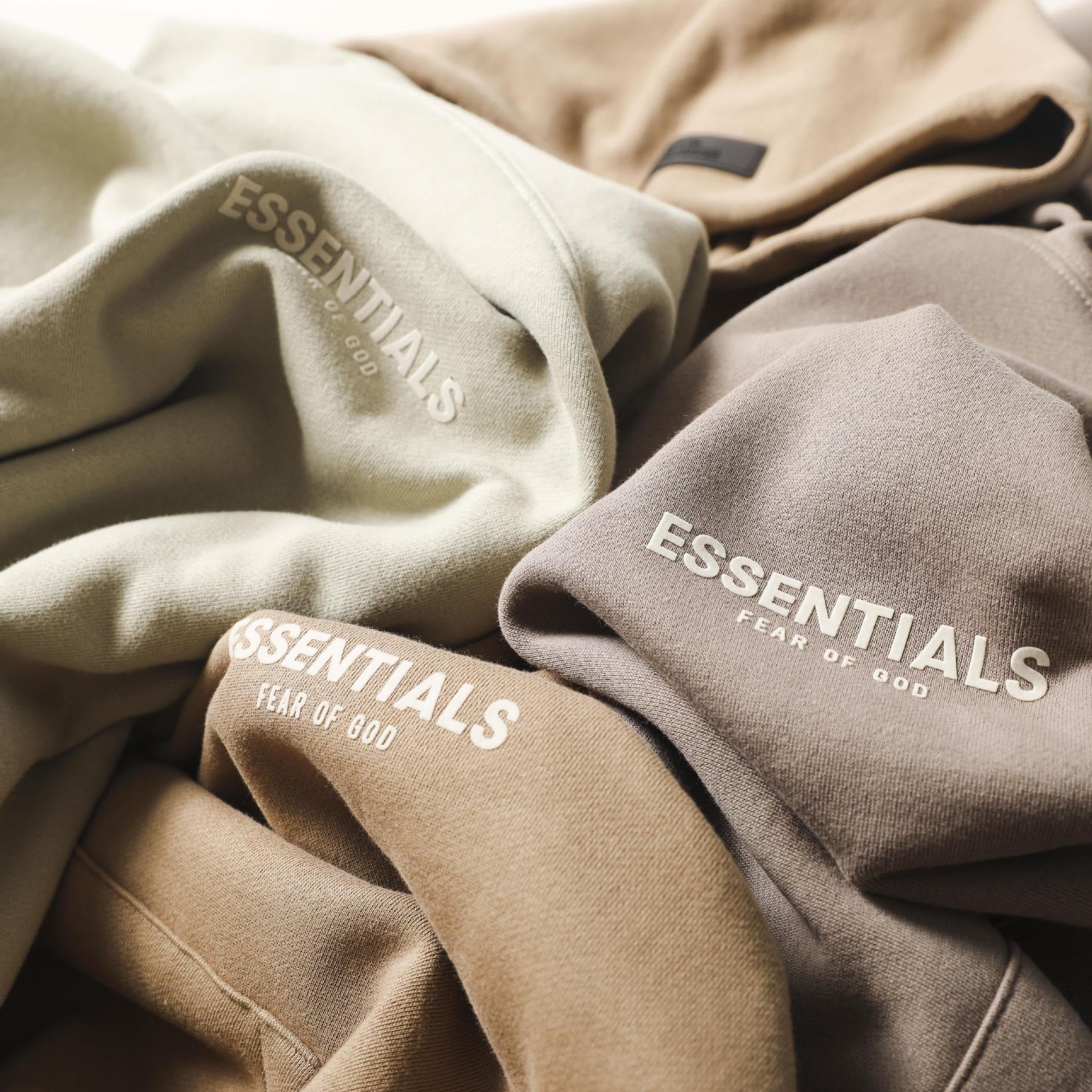 Cozy essentials hoodies with soft, distinctive FOG branding display on a beige and tan background.